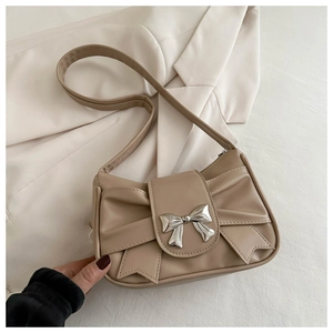Detailed shot of beige bow shoulder bag featuring a silver butterfly buckle on khaki leather