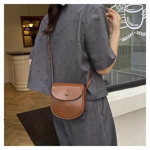 Brown matte saddle bag for women shown worn as a crossbody in a stylish cafe setting