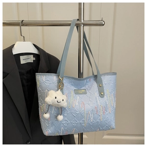 Detail of light blue embossed tote bag with wave embroidery and cloud pendant