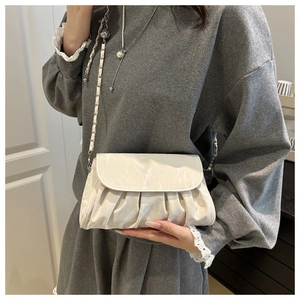 Detailed view of cream-colored cloud bag with pleated texture and silver chain strap