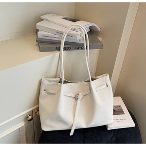 Détail d'un sac cabas tressé blanc avec boucle argentée et texture de tissage