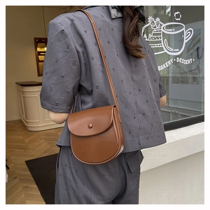 Detailed back view of a brown vintage saddle bag worn by a model in a bakery setting