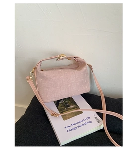 Detail of pink textured fabric shoulder bag with golden metal hooks and leather strap