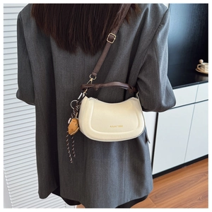 Detail of white half-moon leather shoulder bag with Aitumi 1986 logo and brown charm