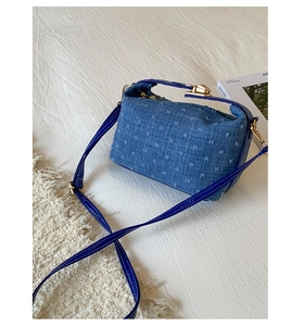 Detail of blue denim shoulder bag with tufted texture and glossy leather strap