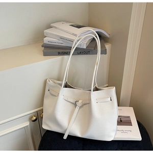 Détail d'un sac cabas en PU blanc tissé avec sangles décoratives et boucles métalliques