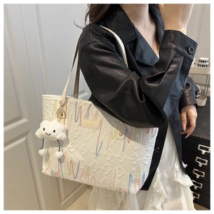 Quilted white canvas tote with wavy embroidery and plush cloud charm accessory