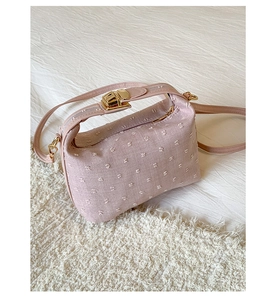 Detail of soft pink fabric handbag with texture dots and golden metallic latch lock
