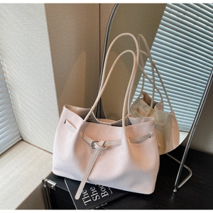 Détail du sac à main rose clair à texture tissée avec boucle et poignées fines