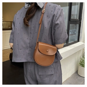 Brown faux leather saddle bag with lychee texture and adjustable strap shown on model