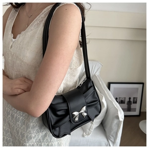 Detail of black pleated PU handbag featuring a metallic silver bow clasp decoration