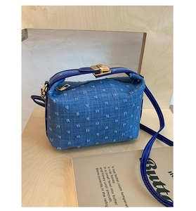 Detail of blue denim crossbody bag with embroidered dots and gold metal hardware