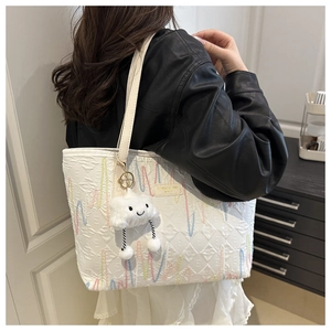 Detail of canvas tote bag featuring colorful wavy embroidery and a cloud plush pendant