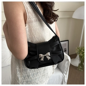 Detail of black underarm bag featuring a metallic bow buckle and pleated design