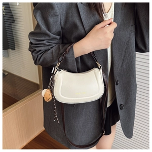 Dettaglio della borsa hobo bianco sporco con logo dorato e ciondolo a forma di orso