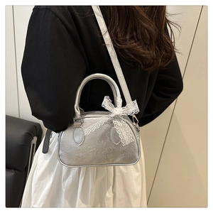 Dettaglio borsa metallica argento con fiocco in pizzo e motivi vintage a rilievo