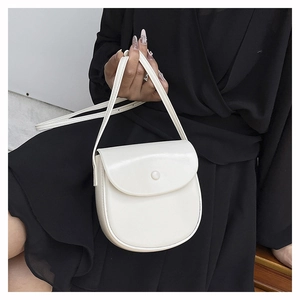 Detail of minimalist creamy white saddle bag featuring smooth matte finish and snap closure