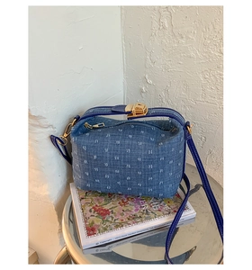 Detailansicht der blauen Denim-Umhängetasche mit Fransenstruktur und goldenem Schloss