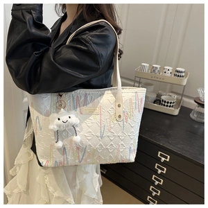 Dettaglio della borsa tote bianca trapuntata con cuciture colorate e ciondolo a nuvola