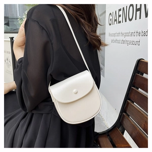 Creamy white semi-circular leather crossbody bag styled on a black chiffon dress