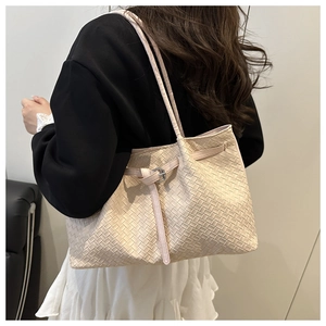 Detailed close-up of beige woven texture and leather strap on a designer bucket bag