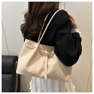 Shoulder shot of a beige woven tote bag with Intrecciato pattern and leather straps