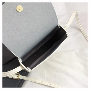 Detail showing white mini crossbody bag interior with gold magnetic closure and red stitching