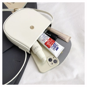 Internal view of a cream white saddle bag showing space for phone and cosmetics