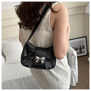 Close-up of a black leather bow-shaped shoulder bag with silver metallic bow buckle