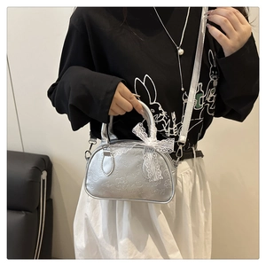 Borsa a mano argento con motivi a rilievo, fiocco in pizzo bianco e tracolla sottile