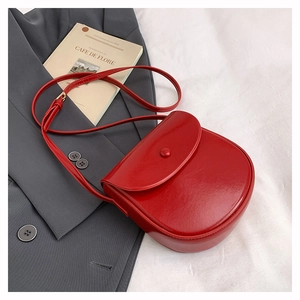 Flat lay of a red saddle crossbody bag on a grey blazer with stylish fashion books