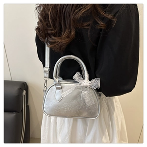 Dettaglio della borsa bowling argento con texture metallica e fiocco di pizzo bianco