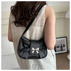 Detail of black PU leather underarm bag with a large bow and silver butterfly clasp