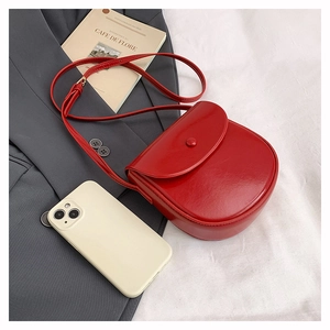 Detail shot of a red leather saddle bag with matching flap and thin shoulder strap