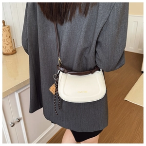Crossbody saddle bag in cream leather shown on model in a stylish commute setting