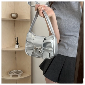 Close-up of silver bow handbag with metallic finish and decorative metal knot detail