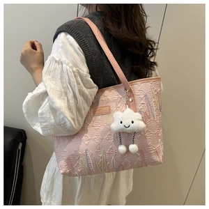 Detailed side view of pink tote bag with rainbow stitching and cloud charm on a model