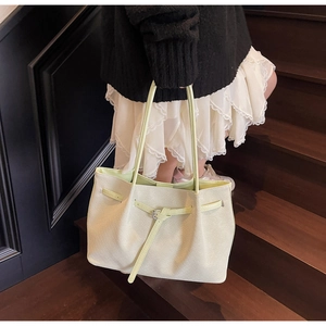 Détail du sac cabas beige tissé avec une sangle décorative et une texture fine