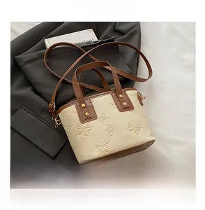 Detailansicht der Mini-Tote mit Schmetterlingsprägung, Kontrastgriffen und Schultergurt