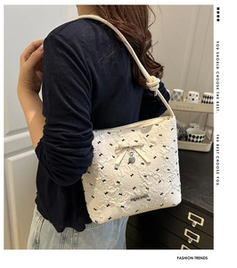 Detail of white embossed bucket bag with black patterns and a knot shoulder strap