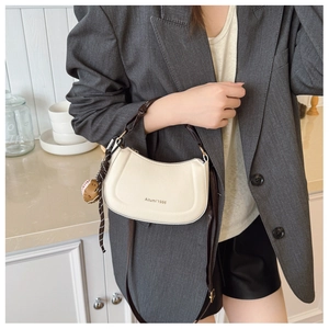 Detail of cream white leather shoulder bag with logo and baseball charm accessory