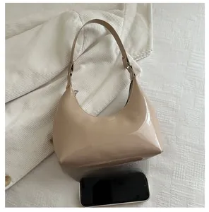 Chic beige patent leather half-moon bag shown next to a smartphone for size reference
