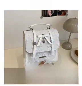 Detail of white PU leather backpack with 3D floral embossing and heart charm pendant