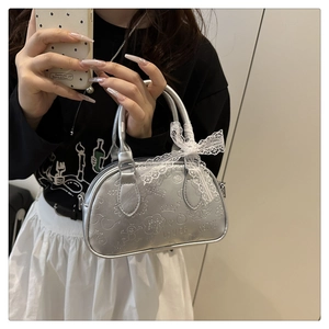 Dettaglio borsa Boston argento metallizzato con motivi a rilievo e fiocco di pizzo