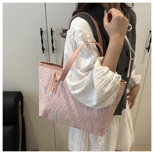 Dettaglio della borsa tote in tela rosa con goffratura testurizzata e ricamo a zigzag