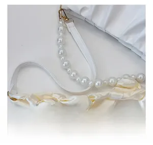 Detail of pearl and satin scarf handles on a white pleated cloud shoulder bag