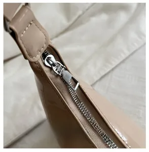 Detail view of the smooth metal zipper and glossy patent leather on a large dumpling bag
