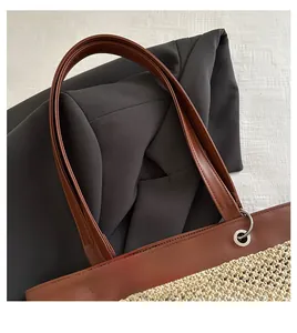 Detail of a minimalist tote bag featuring brown leather straps and woven textured body
