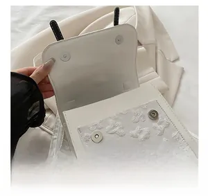 Detail of white PU square bag with floral embroidery and silver magnetic snap closure