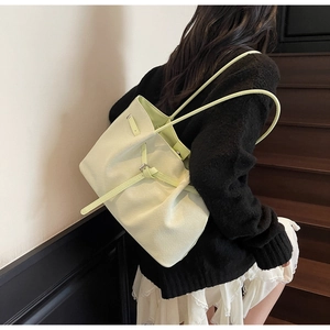 Mannequin portant un sac cabas texturé vert clair sur un fond de mur blanc minimaliste